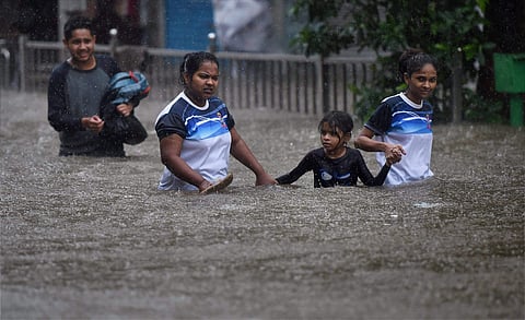 People make their way through a flooded street during heavy rains in Mumbai on Tuesday. | PTI