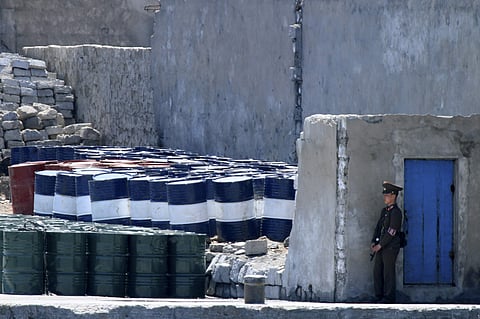 A North Korean soldier stands guard near oil barrels stocked up near the river bank of the North Korean town of Sinuiju, opposite the Chinese border city of Dandong. (AP)