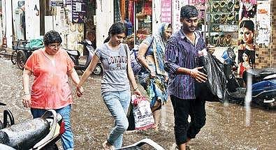 People walking on an already flooded Sowcarpet street caught in a sudden downpour, in the city on Wednesday | MARTIN LOUIS