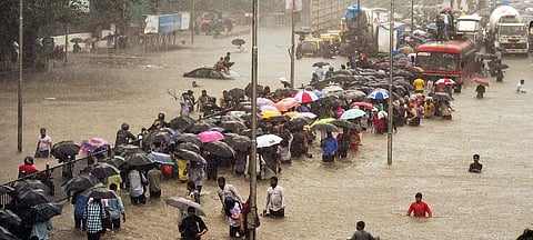 People wade through a flooded street during the heavy downpour in Mumbai on Tuesday | PTI