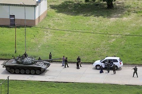 Soldiers stop a vehicle, whose passengers kneel on the ground outside the car, as they detain the two passengers who were circulating on the Paramacay military base in Valencia, Venezuela. | AP