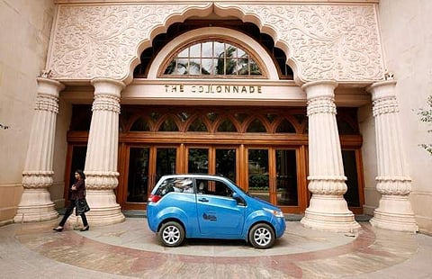 A woman walks past a Mahindra e2o electric car during a media preview in Bengaluru, India, June 8, 2017. | Reuters