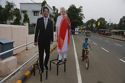 A boy rides his bicycle past cut outs of Japanese PM Shinzo Abe, left and Indian PM Modi put up near Mahatma Gandhi Ashram ahead of Abe's visit in Ahmadabad. (AP)