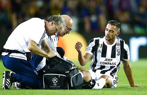 Juventus' Mattia de Sciglio is assisted by a doctor during a group D Champions League match against FC Barcelona at the Camp Nou stadium. | AP