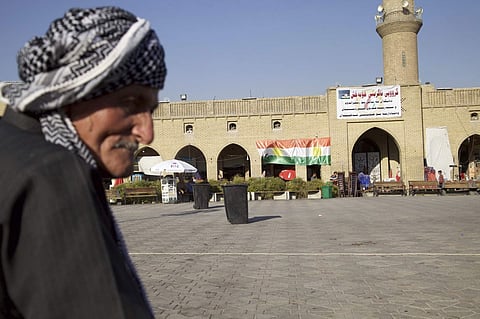 An elderly man sits in the center of Irbil near a campaign poster urging people to vote yes in the upcoming poll on independence from Iraq. (File photo | AP)
