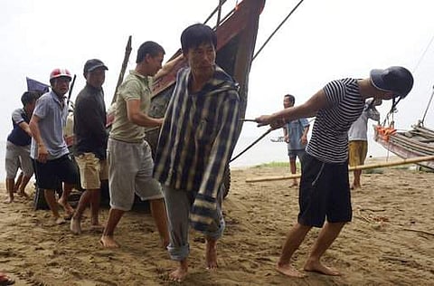 Vietnamese villagers move a fishing boat on shore in northern Thanh Hoa province, Vietnam, Thursday, Sept. 14, 2017. | AP