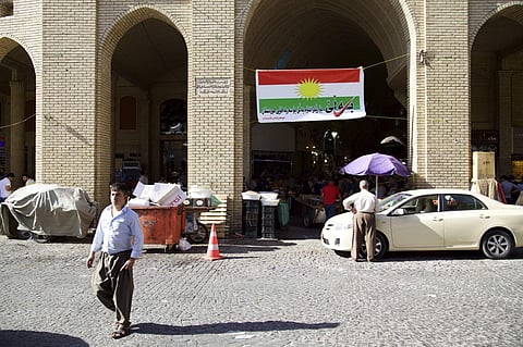 In this Thursday, Aug. 24, 2017 photo, a man walks past a campaign poster printed on a Kurdish flag urging people to vote yes in the upcoming poll on independence from Iraq, Irbil, Iraq. | AP
