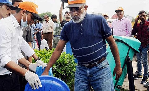 Union Minister Alphons Kannanthanam collecting litter and throwing it in the dustbin at India Gate. (Photo | PTI)