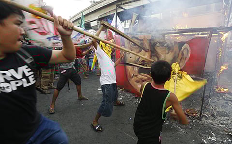 Protesters hit the burning cube effigy with the faces of the late dictator Ferdinand Marcos and President Rodrigo Duterte during a rally near the Presidential Palace to call for an end to the killings in the so-called war on drugs of Duterte and his alleg