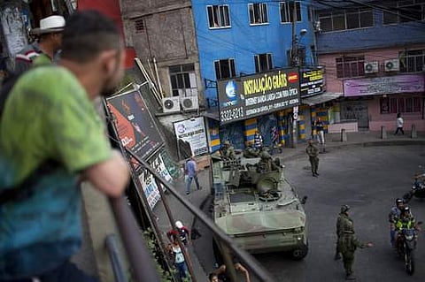 Residents watch an armored vehicle during an operation at the Rocinha favela, in Rio de Janeiro, Brazil, on September 22. (Photo | AP)