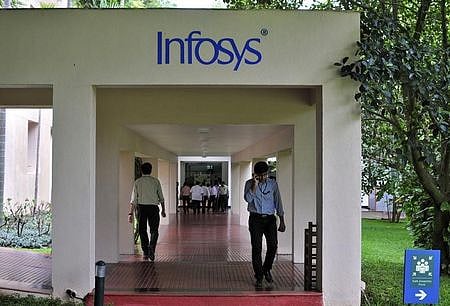 Employees walk along a corridor in the Infosys campus in Bengaluru. (File photo | Reuters)