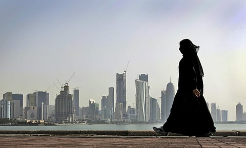 A Qatari woman walks in front of the city skyline in Doha, Qatar. (File photo | AP)