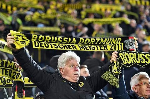 Borussia Dortmund fans hold up their scarves during a match | Photo: AFP