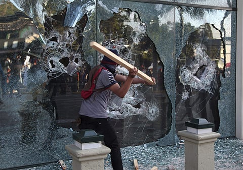 A supporter of opposition presidential candidate Salvador Nasralla shatters a window during clashes with military police. (Photo | AP)