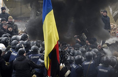 Protesters with a Ukrainian national flag burn tires while clashing with police during a rally outside the Supreme Rada in Kiev. (Photo | AP)