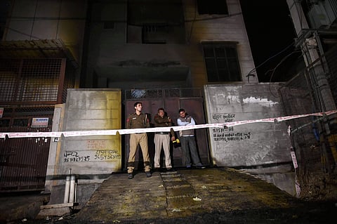 Fire fighters stand outside the two-storey cracker factory which caught fire in north Delhi's Bawana Industrial Area on Saturday. | PTI