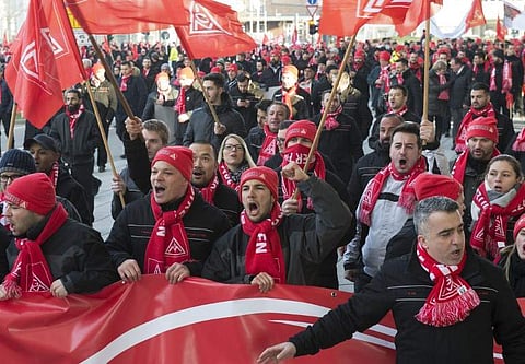 This file photo taken on January 15, 2018 shows employees of German luxury car maker Porsche shouting slogans during a demonstration as part of a warning strike in Stuttgart, southwestern Germany. (AFP)