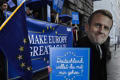 Activist of the AVAAZ network, one with a mask of France's President Emmanuel Macron, attend a demonstration to support the European politic of Macron near the German Social Democratic Party's, SPD, headquarters in Berlin, Thursday, Jan. 11, 2018. (Associ