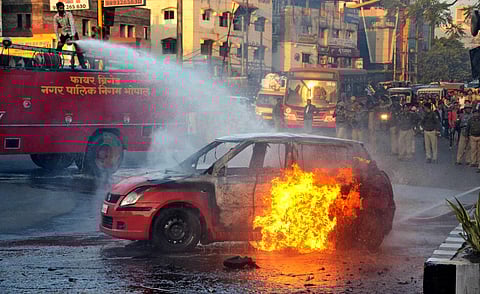 A firefighter tries to douse flames after a car was torched during the anti-PAdmaavat protest on Wednesday. (File | PTI)
