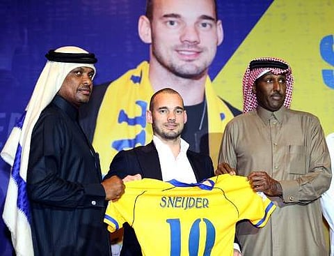 Dutch player Wesley Sneijder (C) poses for a photo with his new jersey during a press conference in Doha as he was officially unveiled by Al-Gharafa football team on January 8, 2018, after signing an 18-month contract with the mid-table Qatari side. (Pho