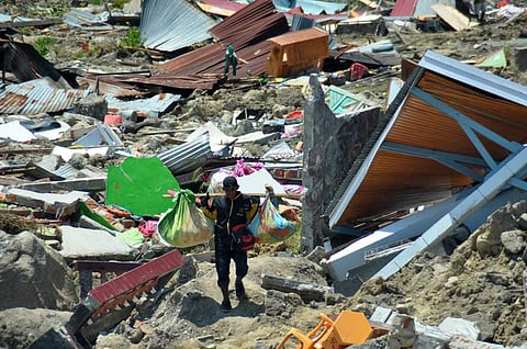 A man carries items he saved from the rubble following a major earthquake and tsunami in Palu, Central Sulawesi, Indonesia. (Photo | AP)