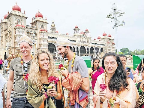Foreign tourists receive a welcome at Mysuru Palace as part of Dasara on Tuesday | Udayashankar S