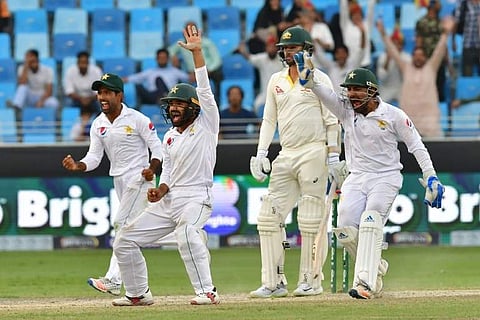 Pakistan cricketers celebrate during day five of the first Test match in the series between Australia and Pakistan at the Dubai International Stadium in Dubai on October 11, 2018. | AFP