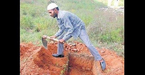 File picture of Ayub Ahmed digging a grave to bury an unclaimed body. He claims to have buried over 10,000 bodies so far | express
