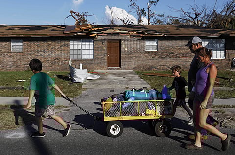 Anthony Weldon, 11, left, pulls a cart with his family's belongings as he relocates with his brother Thomas, 10, mother Dawn Clarke, right, and father Richard Coker from their uninhabitable damaged home to stay at their landlord's place in the aftermath o