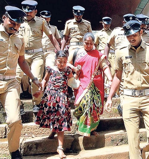 Madhavi and her family being escorted by the police after they were forced to cut short their pilgrimage to the temple on Wednesday | Shaji Vettipuram