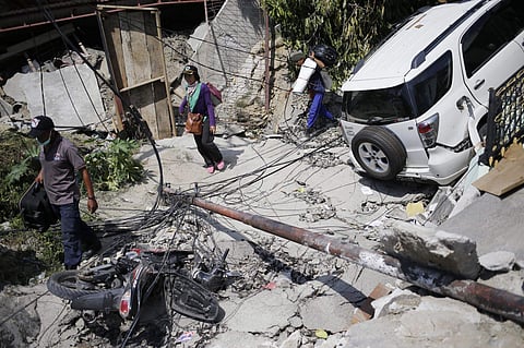 People make their way past vehicles damaged by Friday's earthquake in Palu, Central Sulawesi, Indonesia, Tuesday, Oct. 2, 2018. Desperation was visible everywhere Tuesday among victims receiving little aid in areas heavily damaged by a massive earthquake