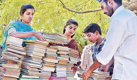 In the shade of the gooseberry tree in the traffic median opposite the VJT Hall, the book collection is progressing.