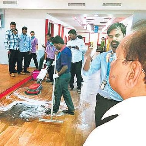 KSPCB chairman watches as RxDx hospital staff clean the black soot accumulated on the floor of the hospital (Photo | Express)