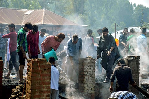 Villagers fouse fire from damaged house where three Lashkar-e-Taiba and Hizbul Mujahideen militants were killed during an encounter with security forces at Redwani area of Kulgam district in south Kashmir on Sunday July 22 2018. | PTI