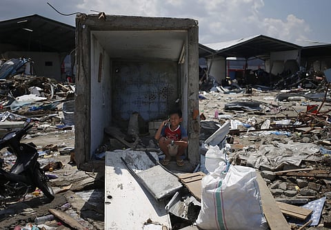 A young boy makes a phone call from an earthquake-damaged bathroom stall in Palu, Central Sulawesi, Indonesia, Wednesday, Oct. 3, 2018. Aid has yet to reach the hardest-hit areas around Palu, the largest city heavily damaged in the earthquake and tsunami