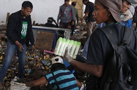 A man holds bottles of body lotion scavenged from an abandoned warehouse following an earthquake and tsunami in Palu, Central Sulawesi, Indonesia. (Photo | AP)
