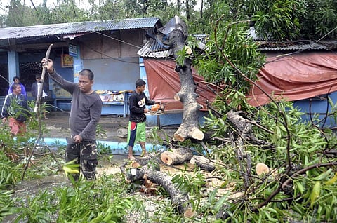 Workers clear the road off toppled trees after Typhoon Yutu slammed Philippines | AP