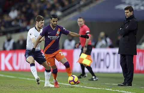 Tottenham's Ben Davies, left, fights for the ball with Manchester City's Riyad Mahrez as Tottenham manager Mauricio Pochettino, right, watches during the English Premier League soccer match between Tottenham Hotspur and Manchester City at Wembley stadium