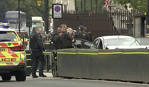 Armed police detain a man who was in a car that crashed into security barriers outside the Houses of Parliament stands to the right of a bus in London.( Photo | AP)