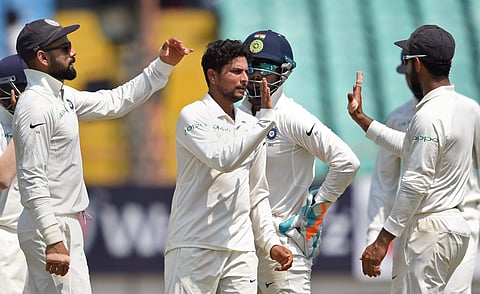 Indian bowler Kuldeep Yadav with his teammates celebrates the wicket of West Indies batsman Shai Hope during their first test cricket match in Rajkot. (Photo | PTI)