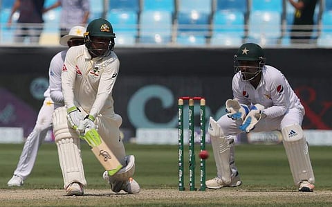Australian cricketer Usman Khawaja (L) plays a shot during the third day of play of the first Test cricket match in the series between Australia and Pakistan at Dubai International Stadium in Dubai. (Photo | AFP)