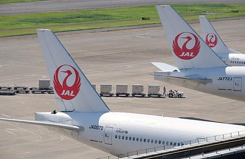 An airport employee works under passenger planes of Japan Airlines at Tokyo's Haneda airport on July 31, 2018. Major Japanese carriers All Nippon Airways (ANA) and Japan Airlines (JAL) on July 31 repo. (Photo | AFP)