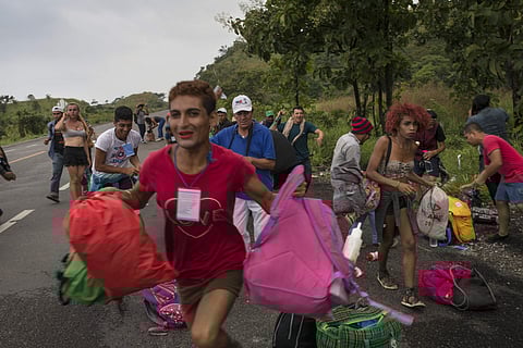LGBTQ group who are traveling with the Central American migrants caravan hoping to reach the US border, run towards a truck who stopped to give them a ride | AP