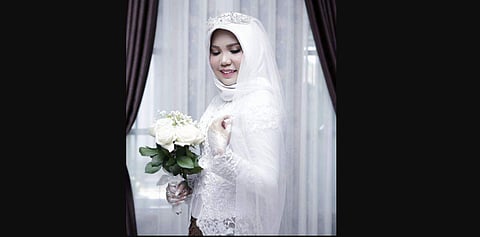 Indonesian Intan Syari poses in her wedding dress with a bouquet of flowers on the day of her planned wedding in Pangkal Pinang, Indonesia. (Photo | AP)