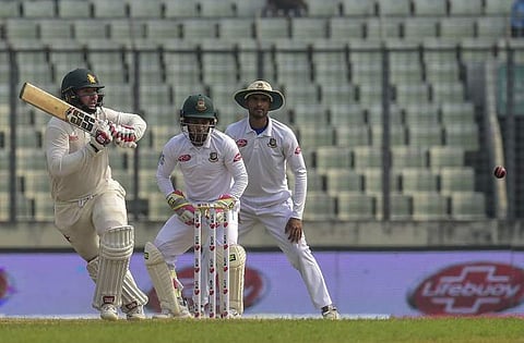 Zimbabwe cricketer Brendan Taylor (L) plays a shot as the Bangladesh cricketer Mushfiqur Rahim (C) and captain Mohammad Mahmudullah (R) look on during the fifth day of the second Test cricket match between Bangladesh and Zimbabwe at the Sher-e-Bangla Nati