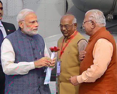 Prime Minister Narendra Modi being welcomed by Haryana Governor Satyadeo Narain Arya and Chief Minister Manohar Lal on his arrival at Farukhnagar village in Gurugram district on Monday. (Photo | PTI)