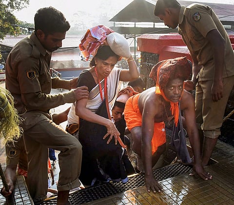 Police personnel assist the devotees to climb up the 18 sacred steps of the Lord Ayyappa temple for offering prayers on the 2nd day of Malayalam month of 'Vrischikom ' (Photo | PTI)