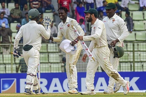 Zimbabwe cricketer Brandon Mavuta (2nd L) celebrates with his teammate Regis Chakabva (L) as Sikandar Raza (2nd R) captain Hamilton Masakadza (R) look on after winning the match during the fourth day of the first Test cricket match between Bangladesh and