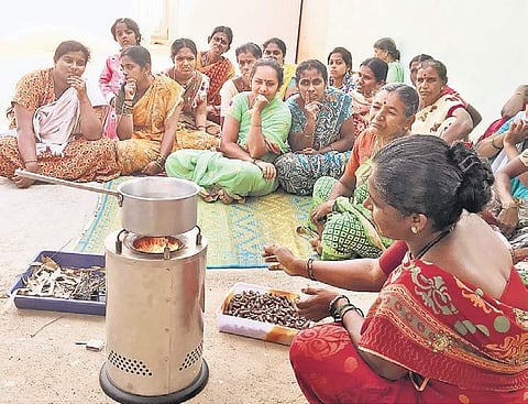 Women from rural parts of the city watch a demonstration of the eco-friendly stove in their village