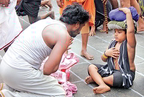 An Ayyappa devotee offering prayers in front of a young devotee at Sannidhanam | Shaji Vettipuram